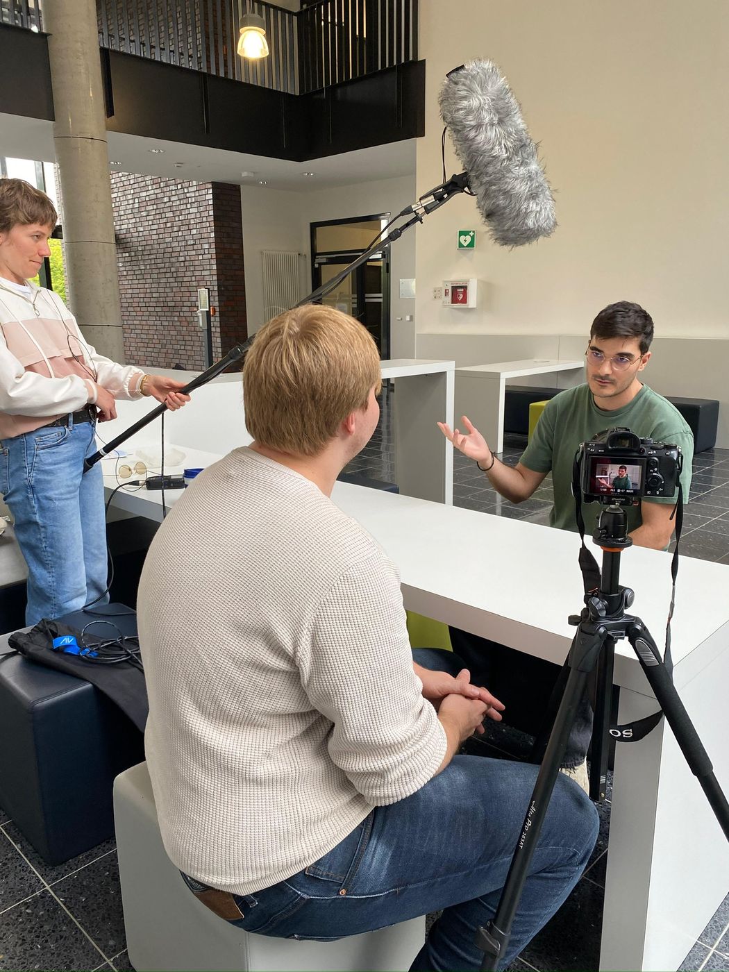Francisco being filmed for an interview, with a camera on a tripod and a boom microphone