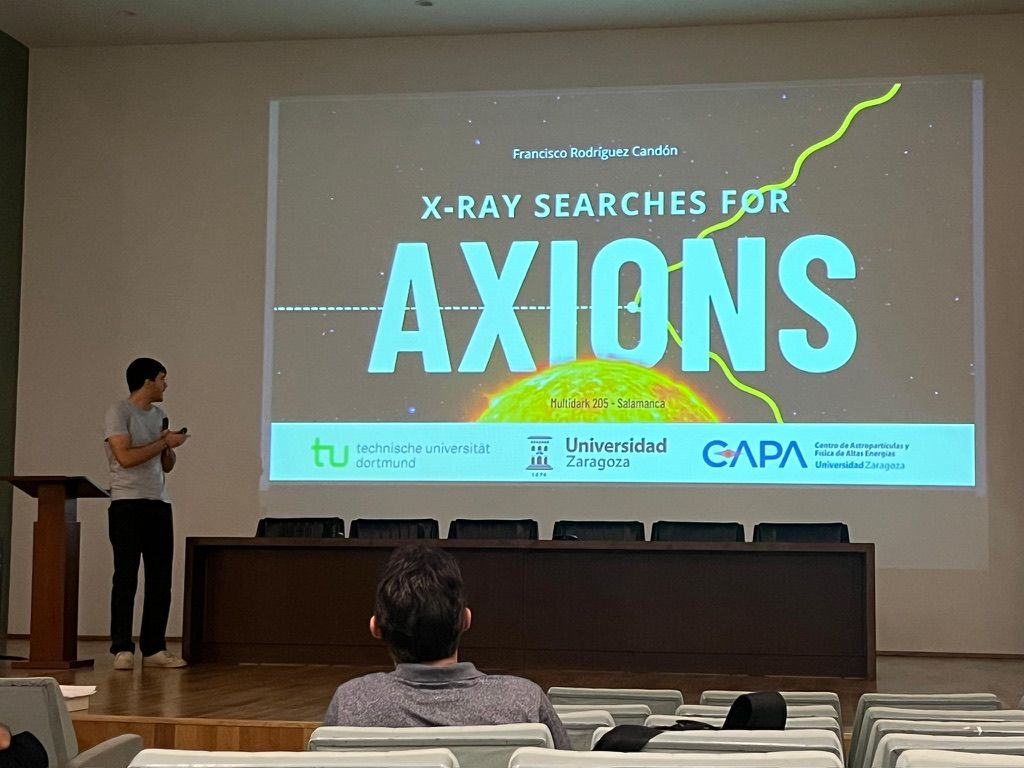 Francisco presenting a title slide reading X-ray searches for axions in a lecture hall