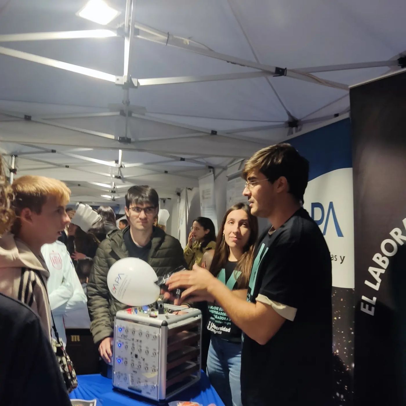 Francisco showing a detector with blue lights to young visitors under a tent
